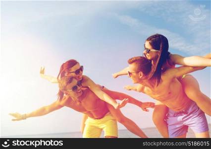 friendship, sea, summer vacation, holidays and people concept - group of smiling friends wearing swimwear and sunglasses having fun on beach. smiling friends having fun on summer beach