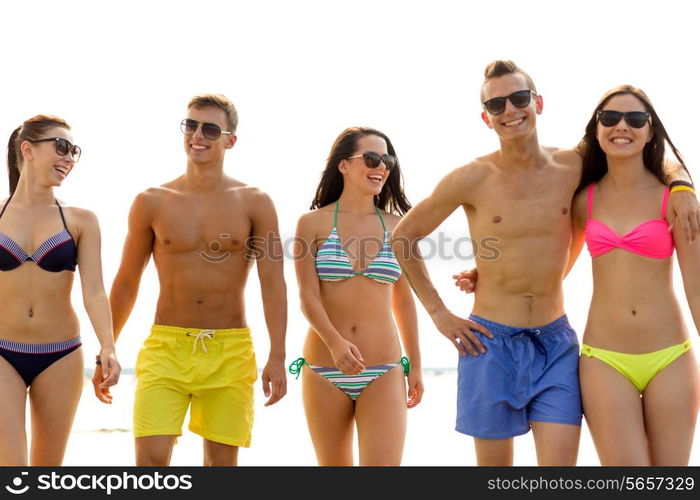 friendship, sea, summer vacation, holidays and people concept - group of smiling friends wearing swimwear and sunglasses walking on beach