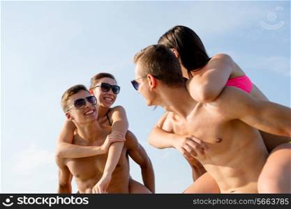 friendship, sea, summer vacation, holidays and people concept - group of smiling friends wearing swimwear and sunglasses having fun on beach