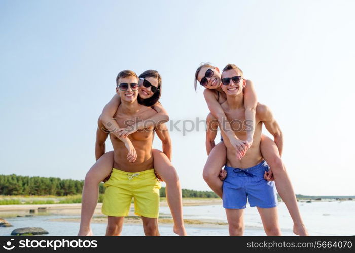 friendship, sea, summer vacation, holidays and people concept - group of smiling friends wearing swimwear and sunglasses having fun on beach