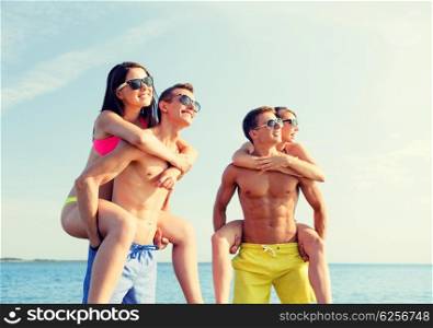 friendship, sea, summer vacation, holidays and people concept - group of smiling friends wearing swimwear and sunglasses having fun on beach