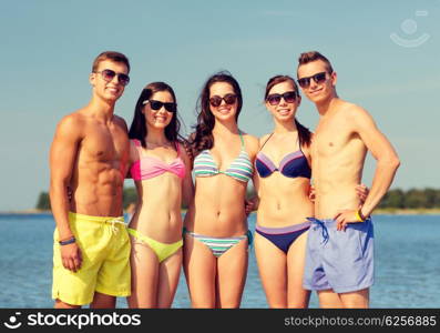 friendship, sea, summer vacation, holidays and people concept - group of smiling friends wearing swimwear and sunglasses on beach