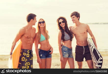 friendship, sea, summer vacation, water sport and people concept - group of smiling friends wearing swimwear and sunglasses with surfboards on beach