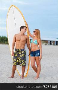 friendship, sea, summer vacation, water sport and people concept - smiling couple in swimwear and sunglasses with surfs on beach