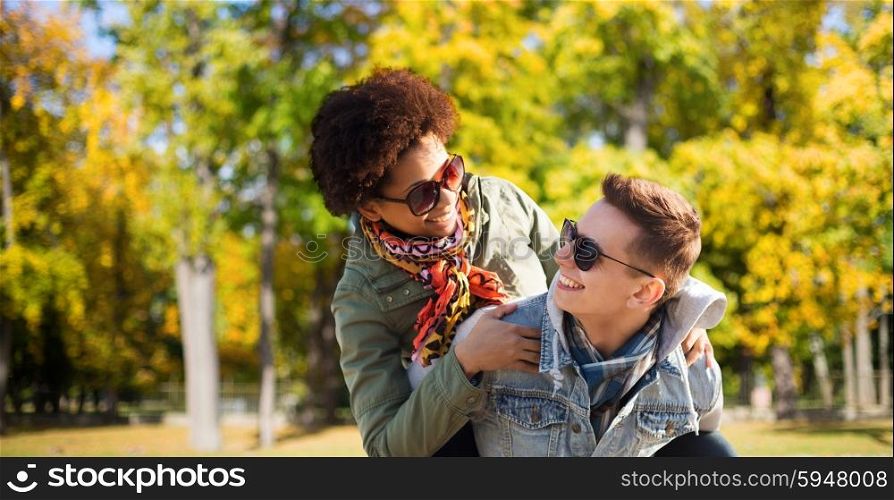 friendship, season, international and people concept - happy teenage couple in shades having fun over autumn park background