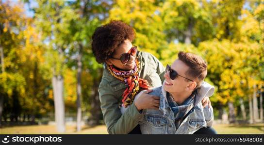 friendship, season, international and people concept - happy teenage couple in shades having fun over autumn park background