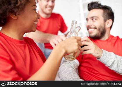 friendship, sport and entertainment concept - close up of happy friends or football fans clinking beer bottles at home. happy friends or football fans with beer at home