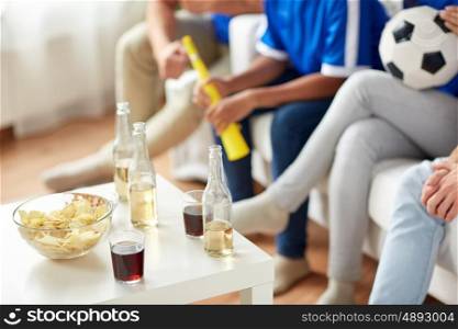 friendship, sport and entertainment concept - football or soccer fans with drinks and chips at home