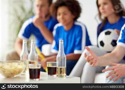 friendship, sport and entertainment concept - football or soccer fans with drinks and chips at home