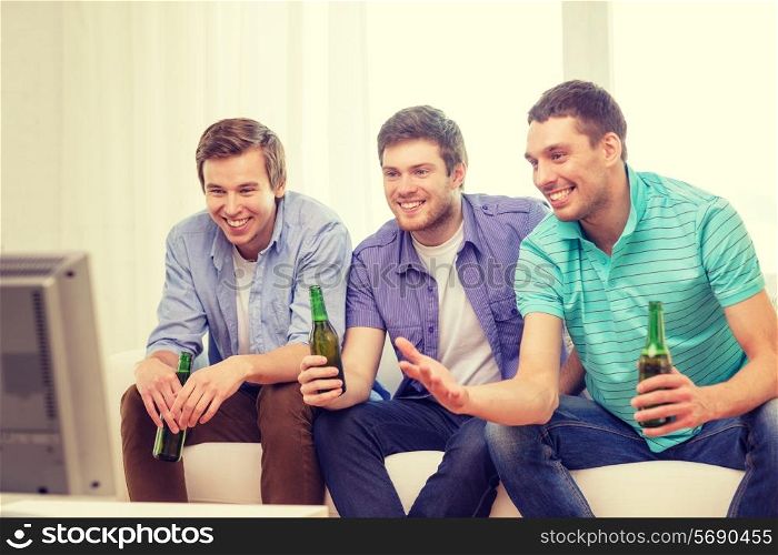 friendship, sports and entertainment concept - happy male friends with beer watching tv at home