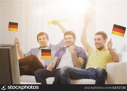 friendship, sports and entertainment concept - happy male friends with flags and vuvuzela supporting football team at home