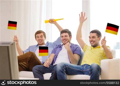 friendship, sports and entertainment concept - happy male friends with flags and vuvuzela supporting football team at home