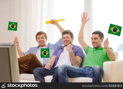 friendship, sports and entertainment concept - happy male friends with flags and vuvuzela supporting football team at home