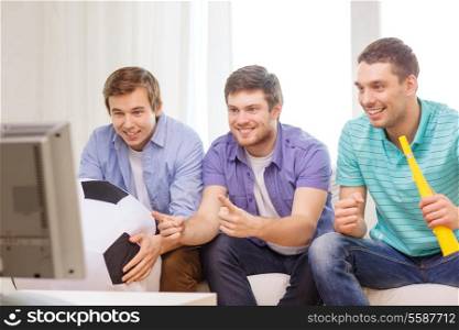friendship, sports and entertainment concept - happy male friends with football and vuvuzela supporting football team at home