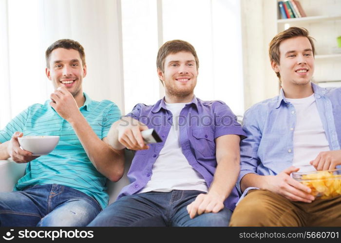 friendship, sports and entertainment concept - happy male friends with snacks watching tv at home