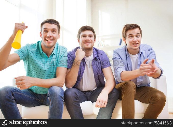 friendship, sports and entertainment concept - happy male friends with vuvuzela supporting football team at home