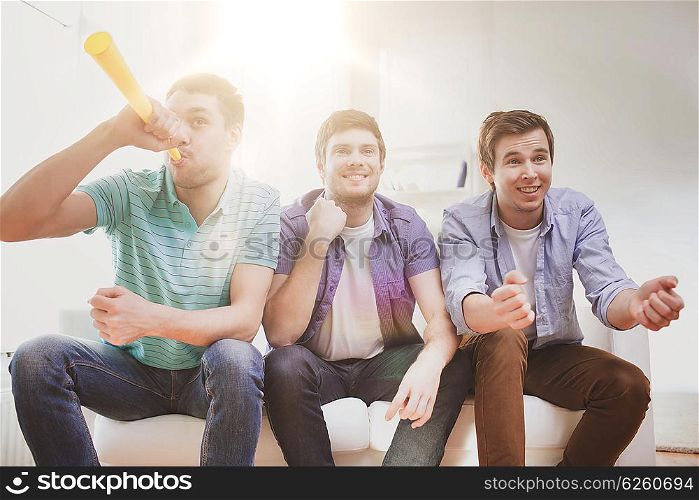 friendship, sports and entertainment concept - happy male friends with vuvuzela supporting football team at home