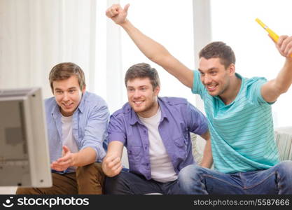 friendship, sports and entertainment concept - happy male friends with vuvuzela watching sports on tv