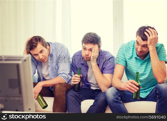 friendship, sports and entertainment concept - sad male friends with beer watching sports on tv at home