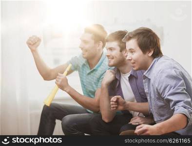 friendship, sports and entertainment - happy male friends with vuvuzela watching sports at home