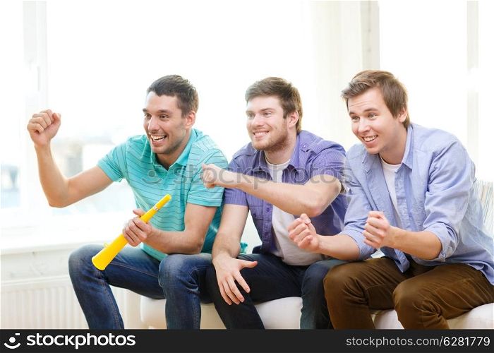 friendship, sports and entertainment - happy male friends with vuvuzela watching sports at home