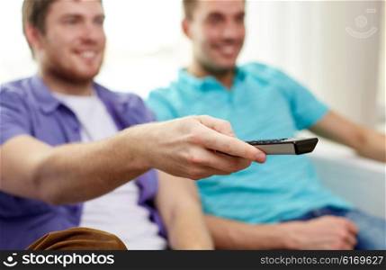 friendship, sports, people and entertainment concept - close up of happy male friends with remote control watching tv at home