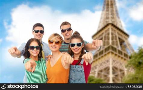 friendship, summer and people concept - group of happy smiling friends in sunglasses pointing at you over eiffel tower background. friends pointing at you over eiffel tower