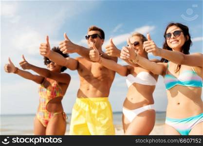 friendship, summer holidays and gesture concept - happy friends on beach showing thumbs up. happy friends showing thumbs up on summer beach