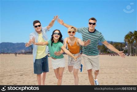 friendship, summer holidays and leisure concept - group of happy smiling friends in sunglasses having fun over venice beach background in california. friends in sunglasses having fun on venice beach