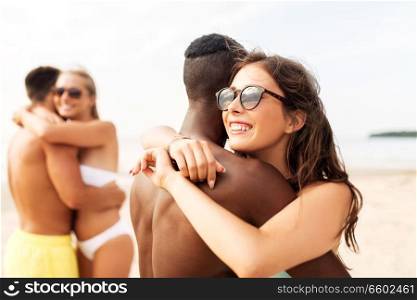 friendship, summer holidays and love concept - happy mixed race couple hugging on beach. happy mixed race couple hugging on beach