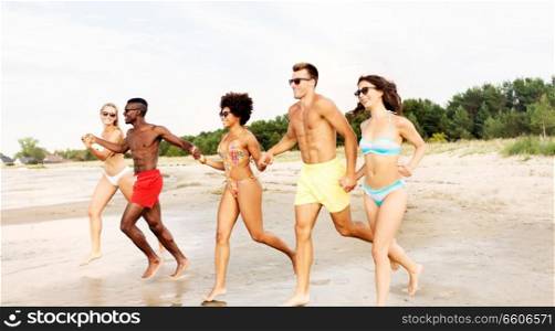 friendship, summer holidays and people concept - happy friends running on beach. happy friends running on summer beach