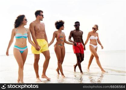 friendship, summer holidays and people concept - happy friends walking along beach. happy friends walking along summer beach