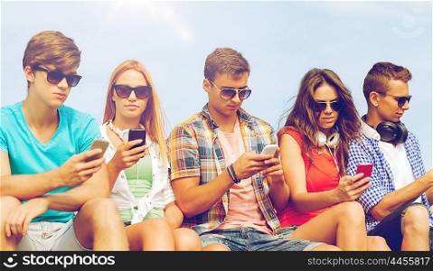 friendship, summer, technology and people concept - group of friends with smartphones and headphones outdoors