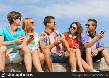 friendship, summer, technology and people concept - group of smiling friends with smartphones and headphones outdoors