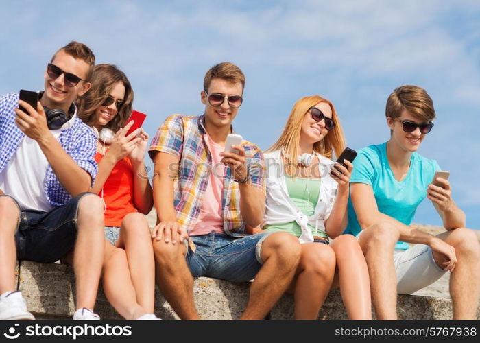 friendship, summer, technology and people concept - group of smiling friends with smartphones and headphones outdoors