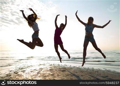 friendship, summer vacation, freedom, happiness and people concept - group of happy female friends dancing and jumping on beach