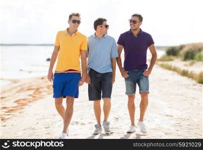 friendship, summer vacation, holidays and people concept - group of smiling male friends in sunglasses walking along beach