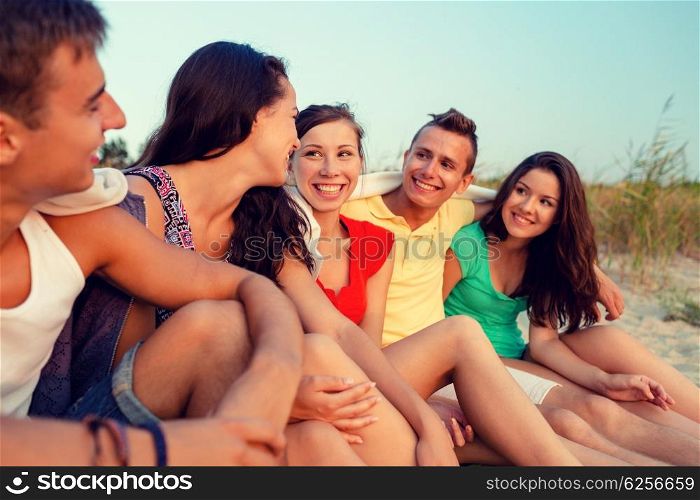 friendship, summer vacation, holidays, gesture and people concept - group of smiling friends sitting on beach