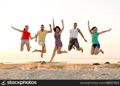 friendship, summer vacation, holidays, party and people concept - group of smiling friends dancing and jumping on beach