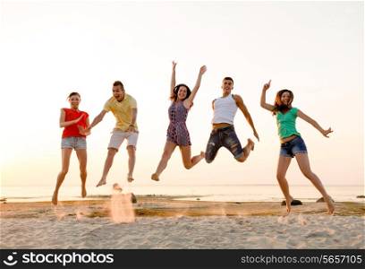 friendship, summer vacation, holidays, party and people concept - group of smiling friends dancing and jumping on beach