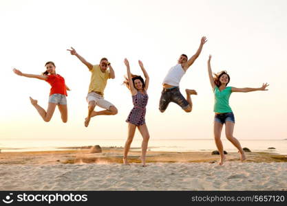 friendship, summer vacation, holidays, party and people concept - group of smiling friends dancing and jumping on beach