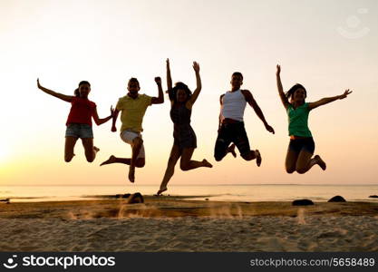 friendship, summer vacation, holidays, party and people concept - group of smiling friends dancing and jumping on beach