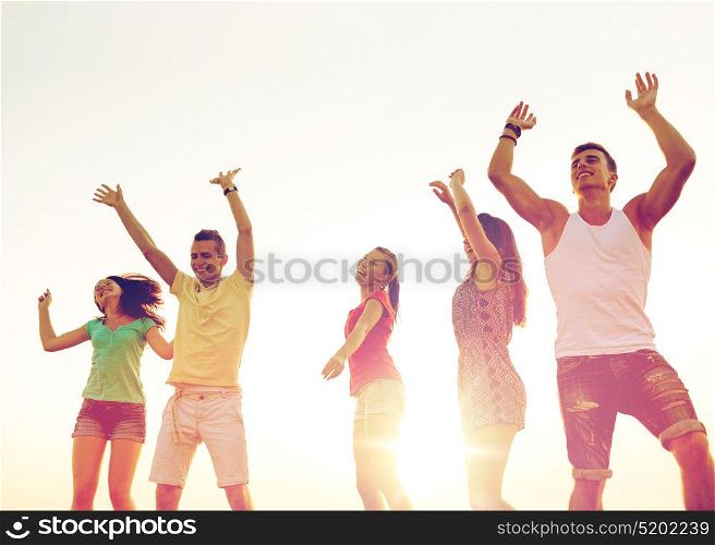 friendship, summer vacation, holidays, party and people concept - group of smiling friends dancing on beach. smiling friends dancing on summer beach