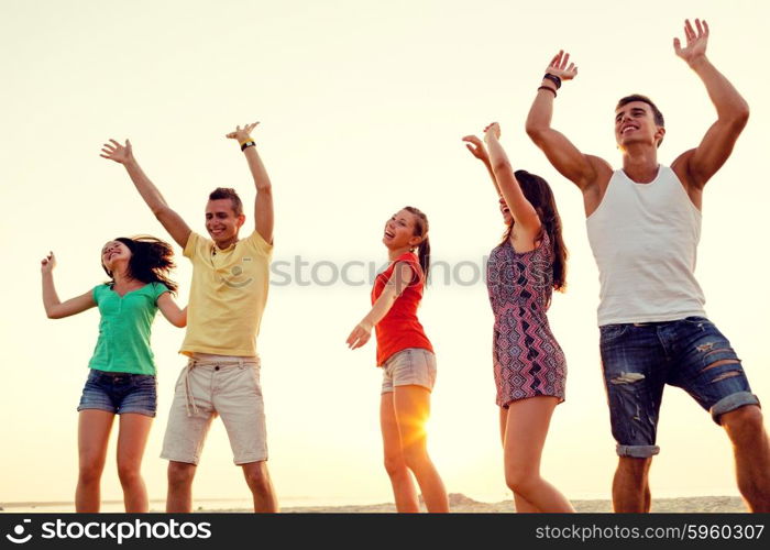 friendship, summer vacation, holidays, party and people concept - group of smiling friends dancing on beach