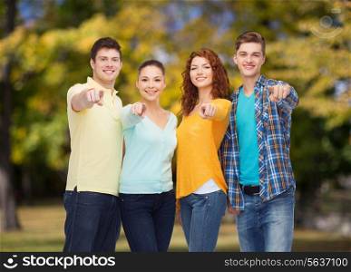 friendship, summer vacation, nature and people concept - group of smiling teenagers pointing finger on you over green park background