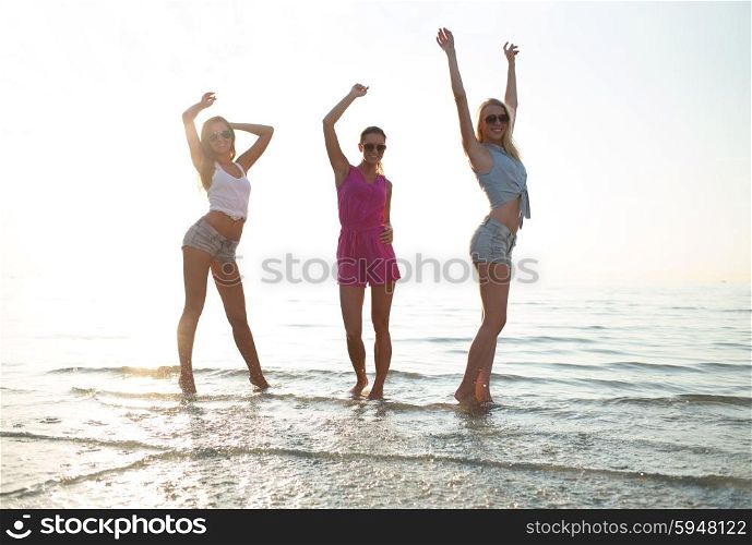 friendship, summer vacation, party, happiness and people concept - group of happy female friends dancing on beach