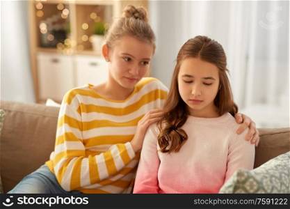 friendship, support and people concept - teenage girl comforting her sad friend at home. teenage girl comforting her sad friend at home