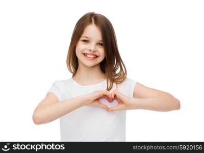 friendship, t-shirt design and happy people concept - smiling little girl in white blank t-shirts showing heart with hands