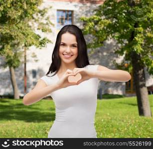 friendship, t-shirt designe and happy people concept - smilinjg girl in white blank t-shirts showing heart with hands