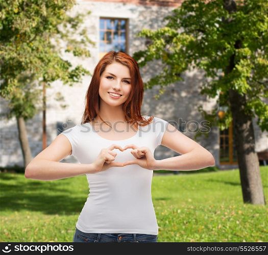 friendship, t-shirt designe and happy people concept - smilinjg girl in white blank t-shirts showing heart with hands